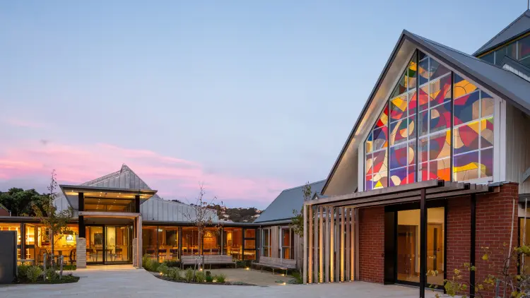 A photograph of the entrance of The Chapel, the colourful abstract stain glass window shines outward into the courtyard space.