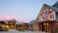 A photograph of the entrance of The Chapel, the colourful abstract stain glass window shines outward into the courtyard space.