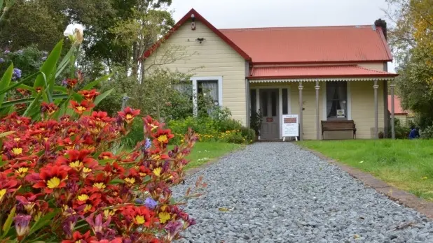 Flower bush and loose stone path leading to timber cottage