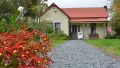 Flower bush and loose stone path leading to timber cottage