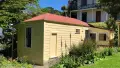 Yellow cottage surrounded by lawn and bushes