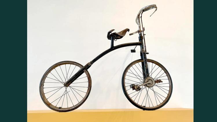 Old two wheeled bike on a brown stand