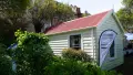 Yellow colonial building with red roof, white banner flag outside and green foliage