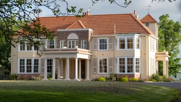 Exterior shot of grand historic homestead with pillars.