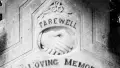 Black and white tombstone with text and engraving of clasped hands