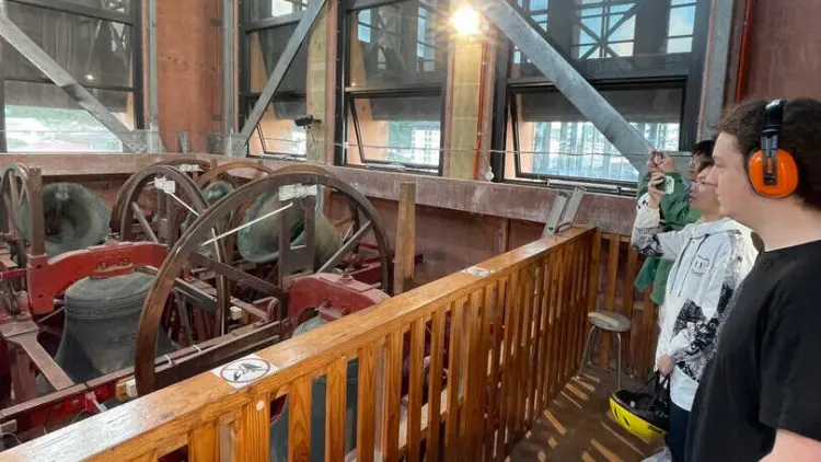 People standing near a bell tower mechanism