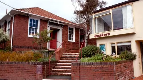 Exterior shot of brick building with stairs, reading Quakers