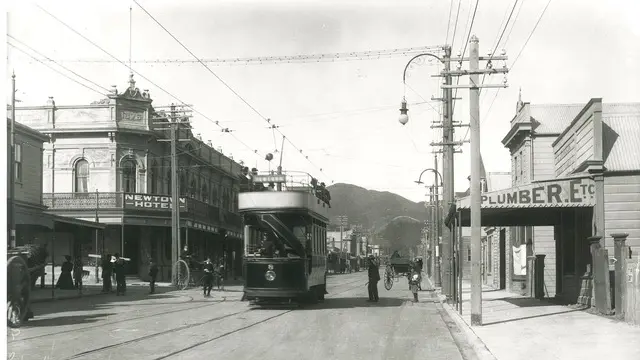 Black and white photograph of a tram and street shops
