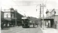 Black and white photograph of a tram and street shops