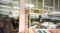 Photograph of a grocers and two people standing in the doorway