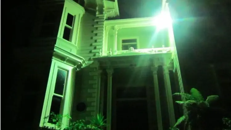 Wooden house lit by a green light in the night