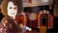 Image of Carmen Rupe staring into the camera with a gallery in the background. 