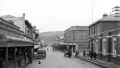 Black and white vintage photo of a street with cars and people.