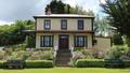 Yellow house in a garden of flowers and a green lawn