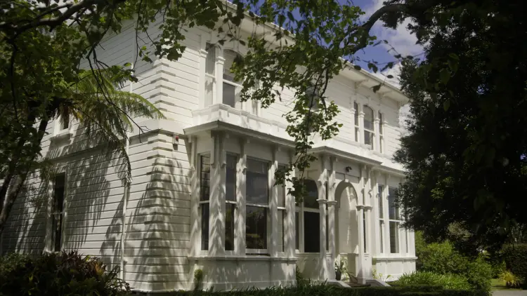 Two story white painted house surrounded by green foliage