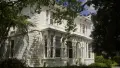 Two story white painted house surrounded by green foliage