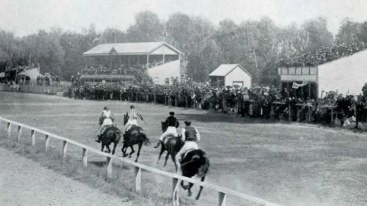 Black and white photo of a horserace at Tauherenikau Racecourse