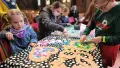 Colour photograph of children pasting paper crafts on a table with a black and white pattern.