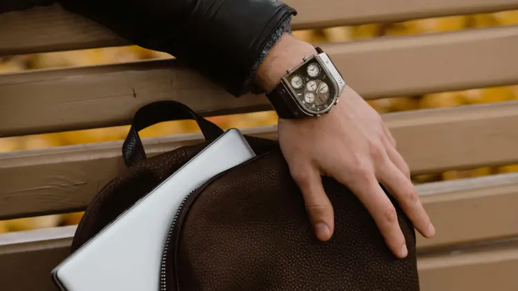 Hand with a watch on the wrist resting on an open backpack