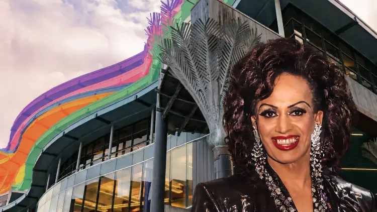 Transgender woman and drag performer Carmen Rupe in front of rainbow coloured Wellington Central Library