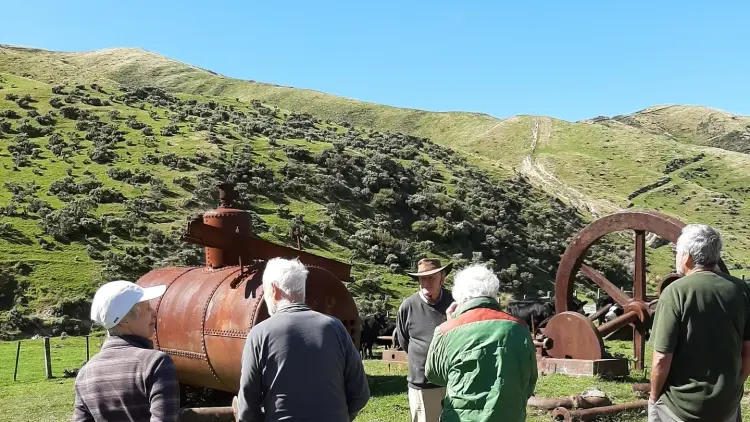 Group of people in front of old machinery and rolling hills