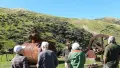 Group of people in front of old machinery and rolling hills